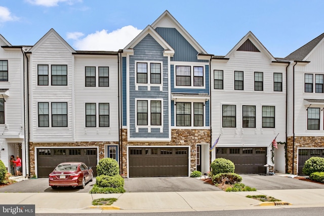 townhome / multi-family property featuring stone siding, a garage, driveway, and board and batten siding