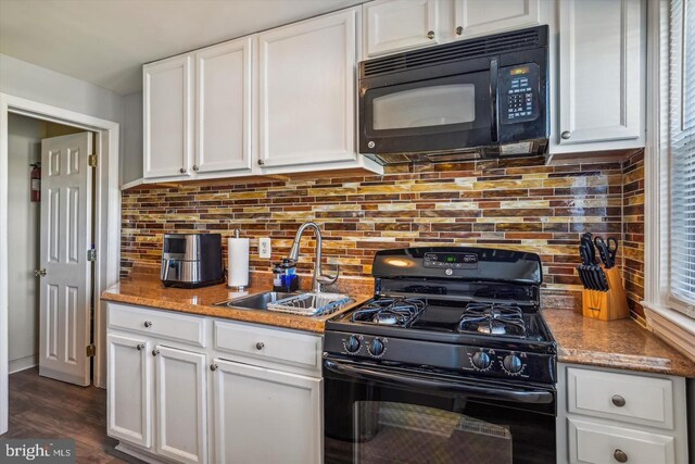 kitchen featuring white cabinetry, black appliances, decorative backsplash, and a sink