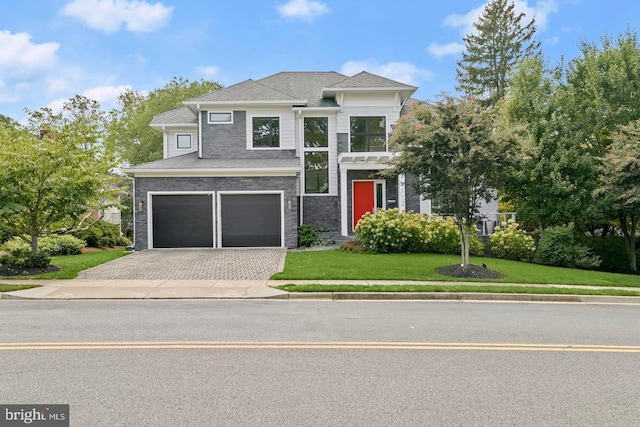modern home with an attached garage, decorative driveway, and a front lawn