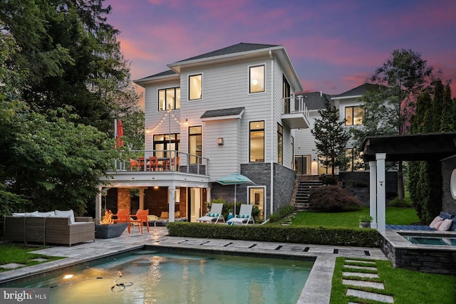 4012 N Upland St, Arlington, VA 22207 - back of house at dusk featuring a balcony, outdoor lounge area, an in-ground hot tub, and an outdoor pool