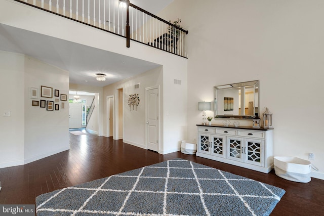 entrance foyer featuring wood finished floors, a towering ceiling, baseboards, and stairway