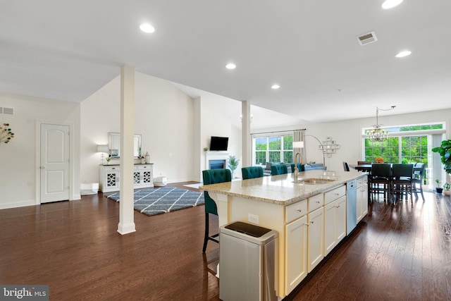 kitchen with a sink, plenty of natural light, dark wood-style flooring, light stone countertops, and recessed lighting