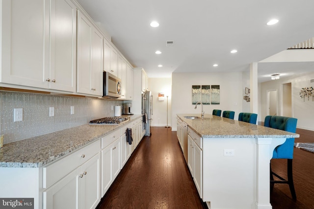 kitchen with stainless steel appliances, a sink, a breakfast bar area, dark wood-style flooring, and recessed lighting