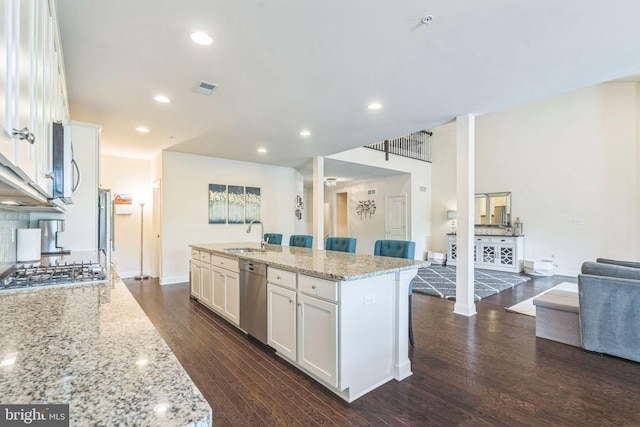 kitchen with appliances with stainless steel finishes, dark wood-style flooring, white cabinets, a sink, and recessed lighting