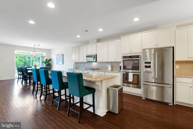 kitchen featuring appliances with stainless steel finishes, tasteful backsplash, dark wood-style floors, a chandelier, and white cabinetry