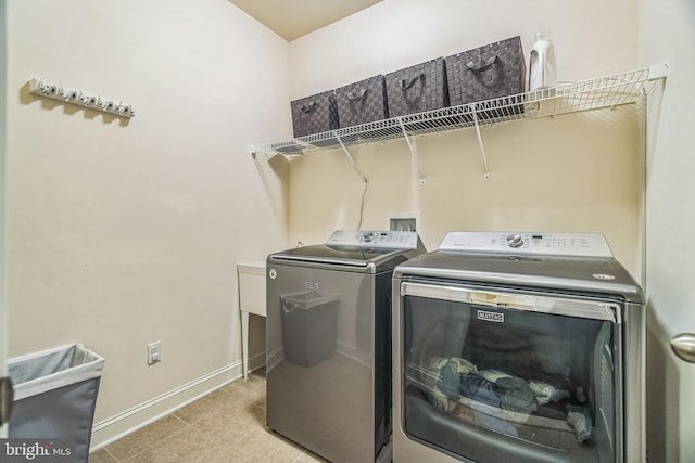 clothes washing area with independent washer and dryer, baseboards, and tile patterned floors