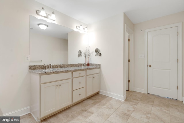 full bath with double vanity and baseboards
