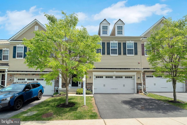 multi unit property featuring a garage, driveway, and stone siding