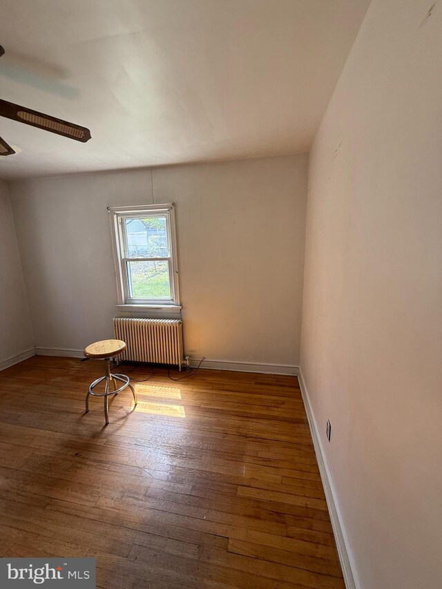 1127 45th Pl SE, Washington, DC 20019 - unfurnished room featuring baseboards, radiator heating unit, a ceiling fan, and hardwood / wood-style flooring