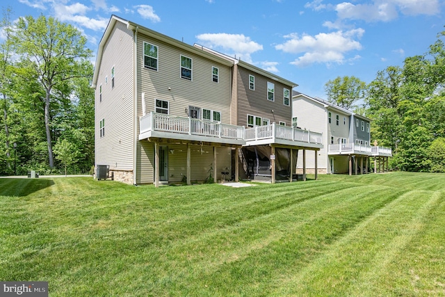 rear view of property featuring a deck, a yard, and central AC