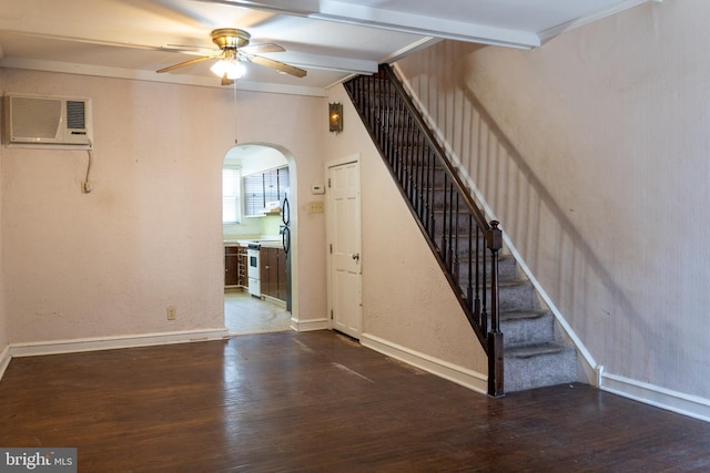 interior space featuring a wall unit AC, arched walkways, a ceiling fan, and wood finished floors