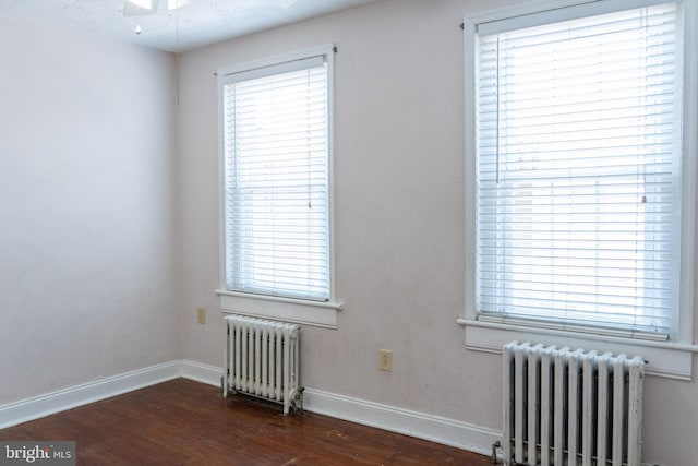 unfurnished room with radiator, wood finished floors, and baseboards