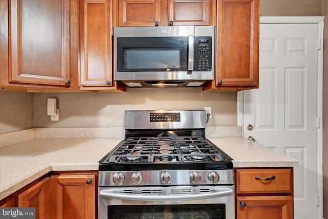 kitchen with stainless steel appliances, light countertops, and brown cabinetry