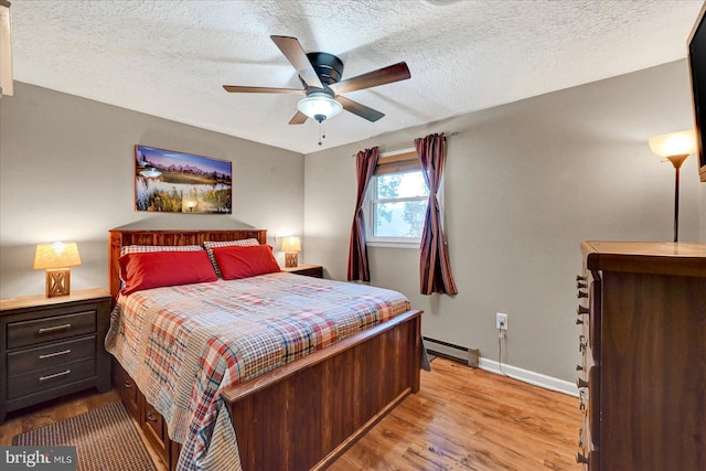 bedroom with a baseboard radiator, wood finished floors, baseboards, ceiling fan, and a textured ceiling