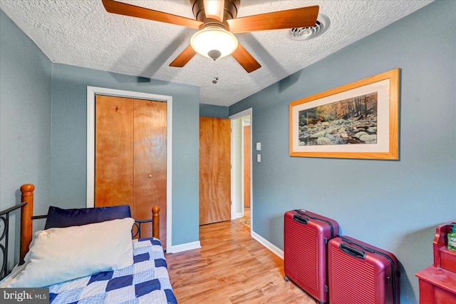 bedroom featuring a textured ceiling, wood finished floors, baseboards, a closet, and ceiling fan