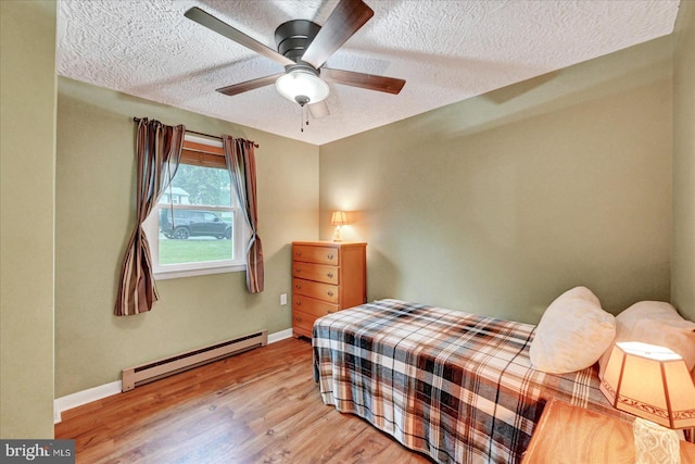 bedroom with a baseboard radiator, wood finished floors, baseboards, a textured ceiling, and a ceiling fan