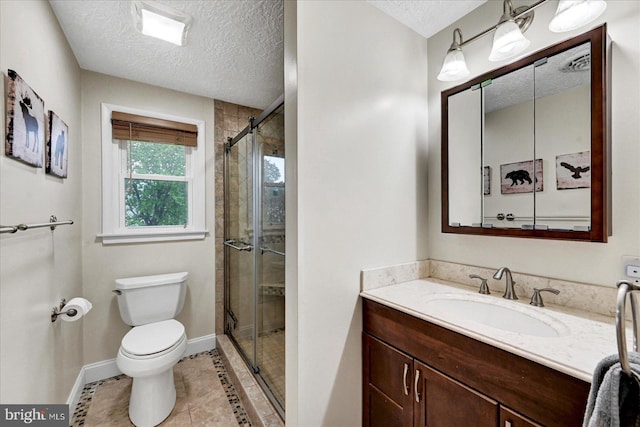 bathroom featuring a textured ceiling, toilet, a stall shower, baseboards, and vanity
