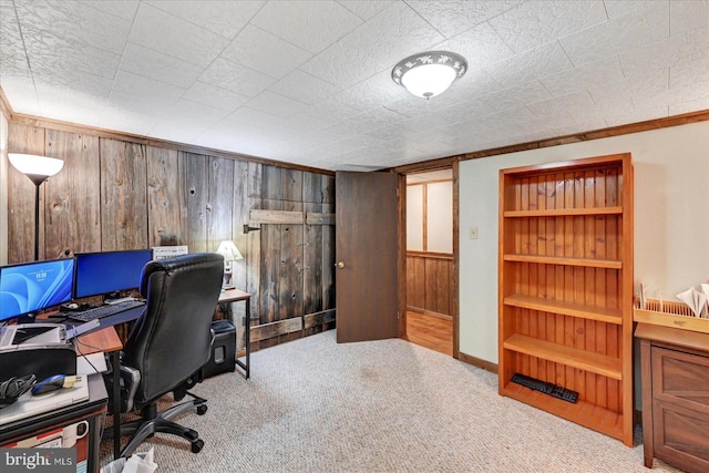 carpeted home office featuring wood walls, built in features, and baseboards