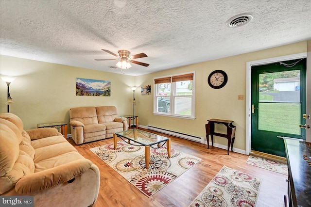 living area featuring baseboard heating, ceiling fan, wood finished floors, baseboards, and a textured ceiling