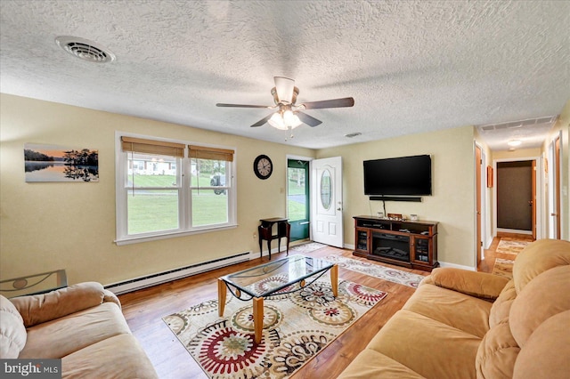 living area featuring baseboard heating, ceiling fan, wood finished floors, a textured ceiling, and baseboards