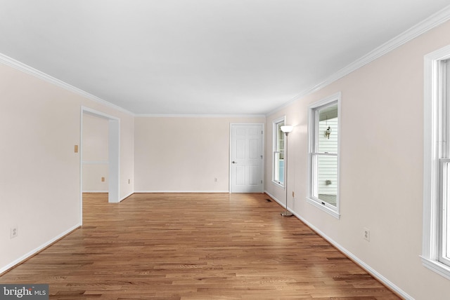 unfurnished room with light wood finished floors, crown molding, and baseboards