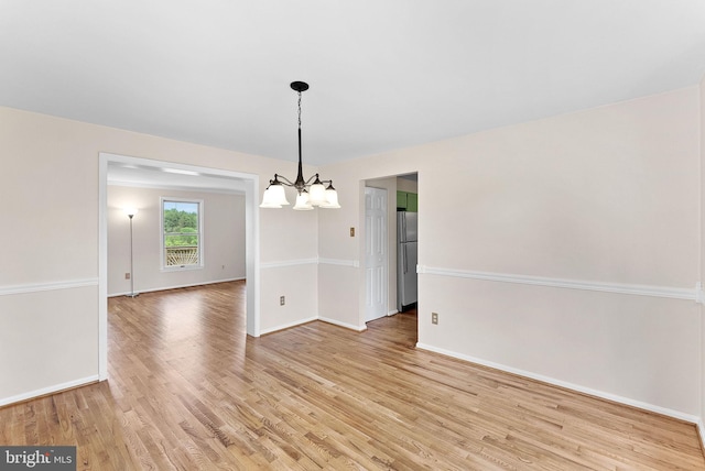 unfurnished dining area featuring a chandelier, light wood-type flooring, and baseboards