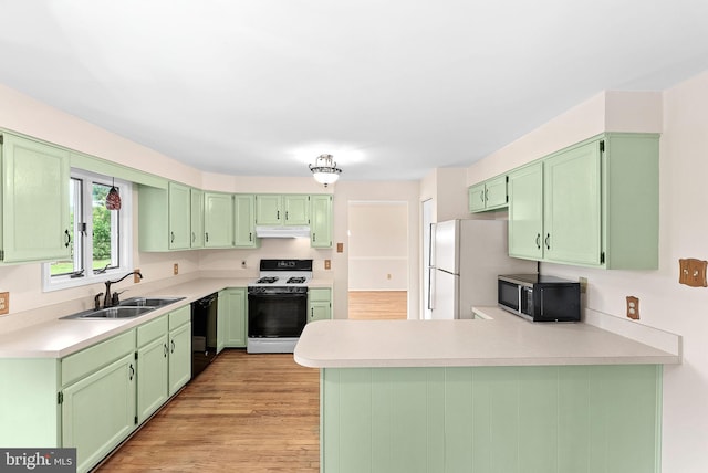 kitchen featuring white appliances, a sink, under cabinet range hood, a peninsula, and green cabinets