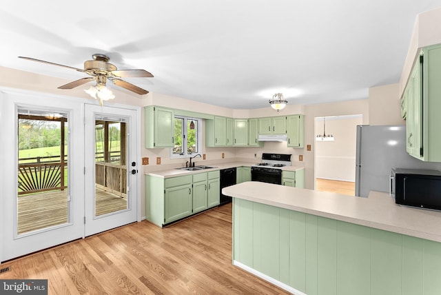 kitchen with green cabinets, range with gas stovetop, a peninsula, under cabinet range hood, and light countertops