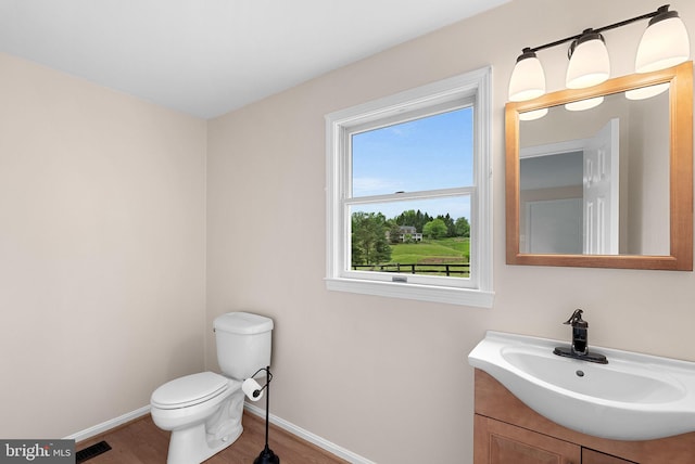 half bathroom featuring baseboards, wood finished floors, toilet, and vanity