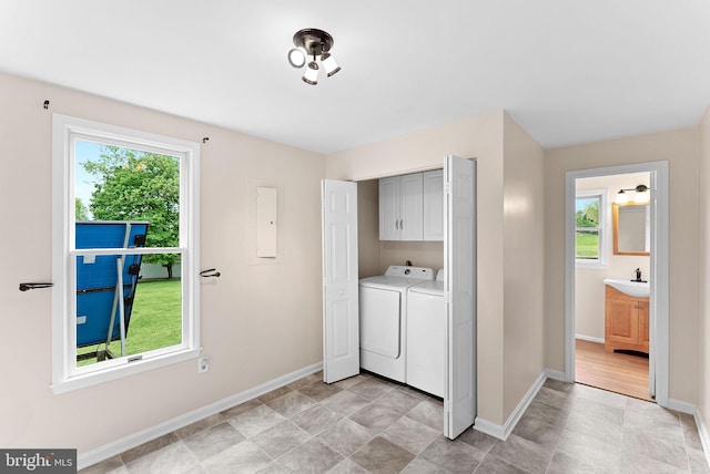 washroom featuring cabinet space, baseboards, plenty of natural light, and washing machine and dryer