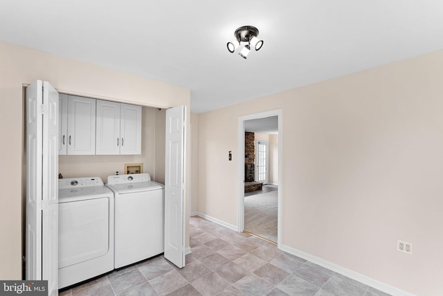 laundry area featuring cabinet space, washer and clothes dryer, baseboards, and stone finish floors
