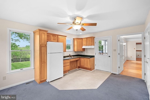 kitchen featuring freestanding refrigerator, under cabinet range hood, ceiling fan, and healthy amount of natural light
