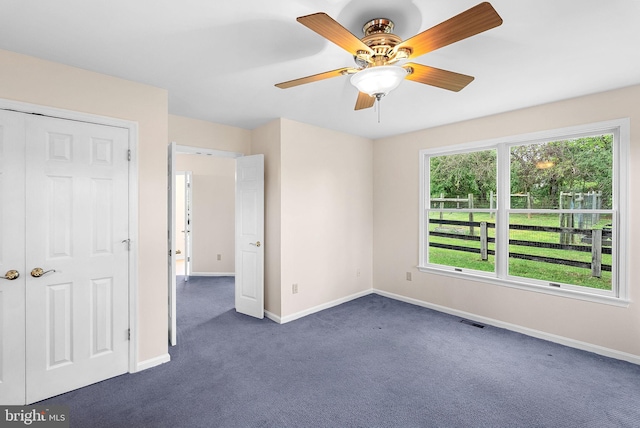 unfurnished bedroom with dark carpet, baseboards, and a ceiling fan
