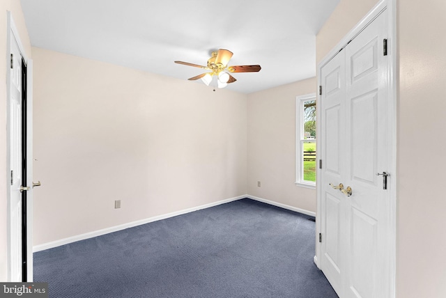 unfurnished bedroom with dark colored carpet, baseboards, and a ceiling fan