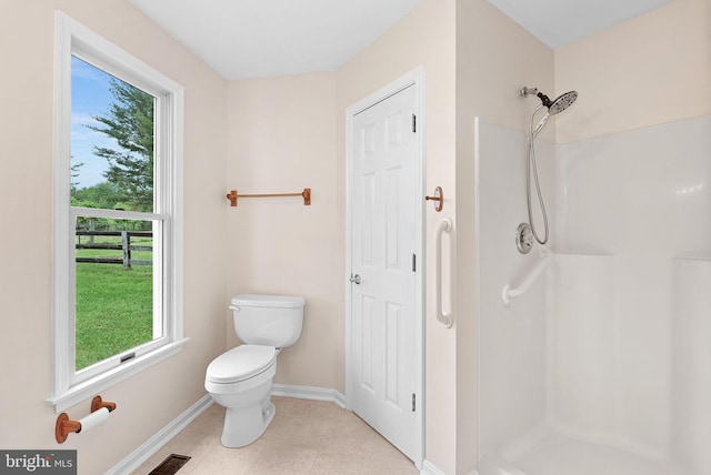 full bathroom featuring baseboards, a stall shower, plenty of natural light, and toilet