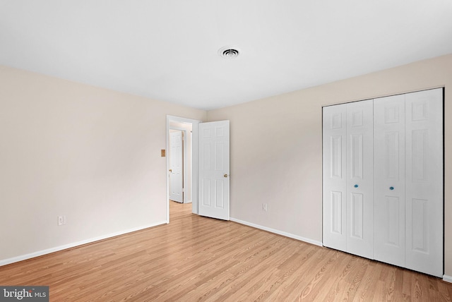 unfurnished bedroom featuring wood finished floors, baseboards, and a closet