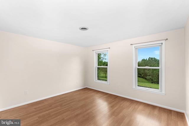unfurnished room with baseboards and light wood-type flooring