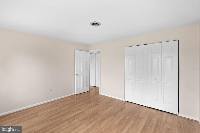 unfurnished bedroom with baseboards, light wood-type flooring, and a closet