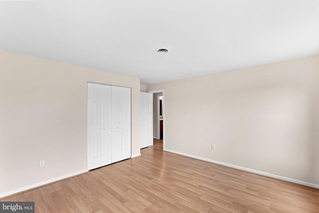 unfurnished bedroom featuring baseboards, light wood-type flooring, and a closet
