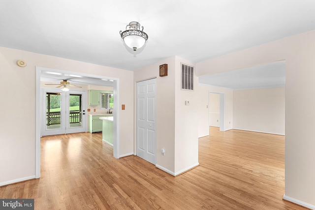 empty room featuring light wood-style flooring, baseboards, a smoke detector, and ceiling fan