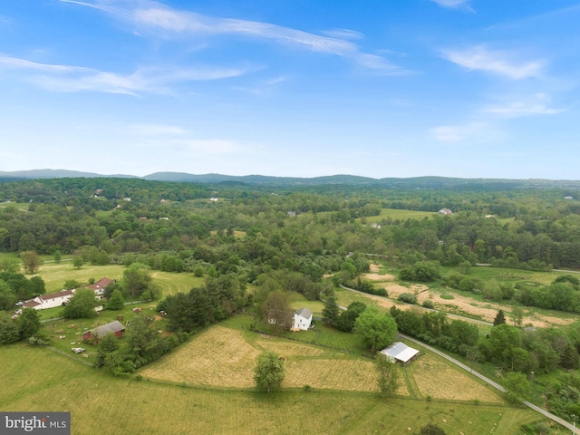 view of property location with a mountain backdrop, rural landscape, and a forest