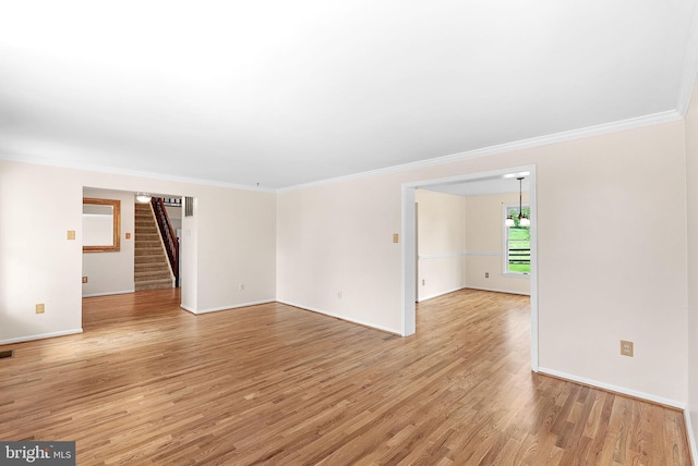 spare room featuring stairs, crown molding, baseboards, and light wood-style floors