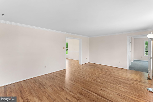 empty room with ornamental molding, baseboards, and light wood-type flooring