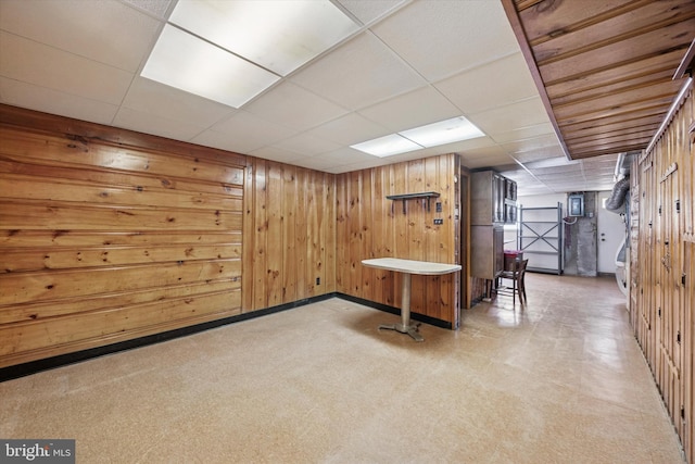 finished below grade area featuring wood walls, baseboards, and a drop ceiling