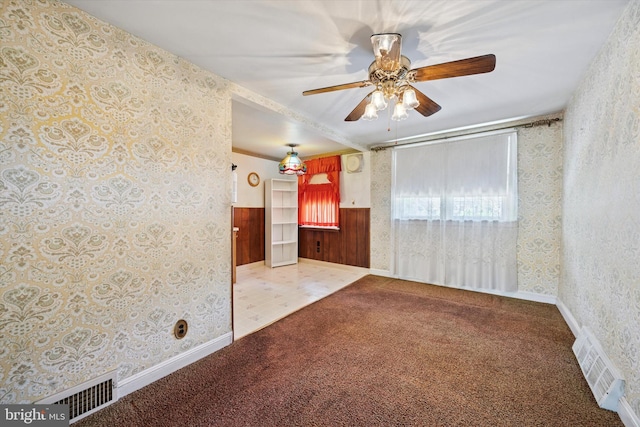 carpeted spare room featuring wallpapered walls and ceiling fan