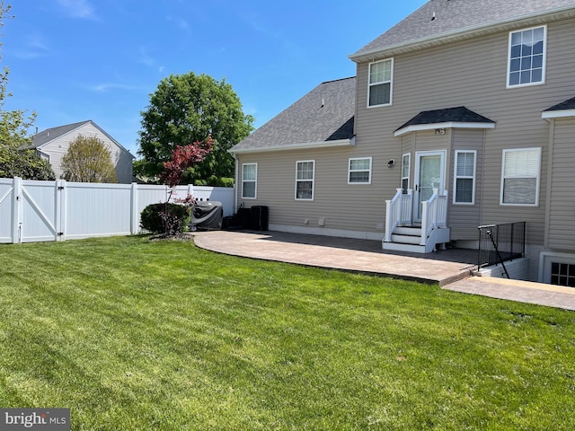 rear view of house featuring a patio, a shingled roof, fence, and a gate
