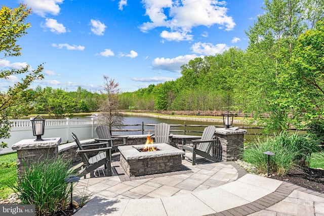 view of patio / terrace with an outdoor fire pit, a water view, and fence