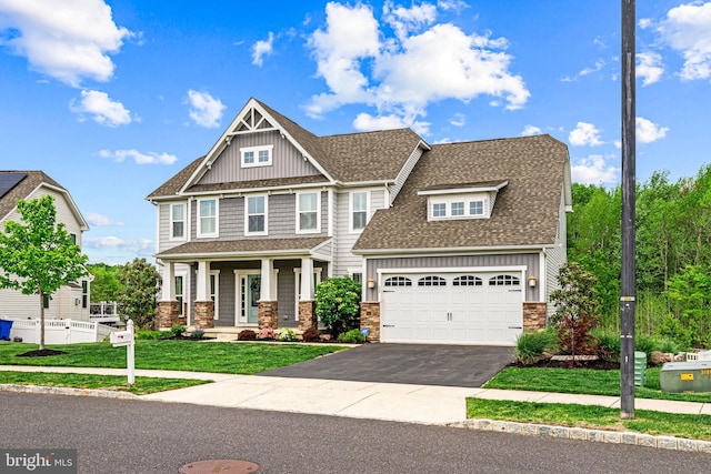 craftsman-style house with a porch, roof with shingles, stone siding, driveway, and board and batten siding