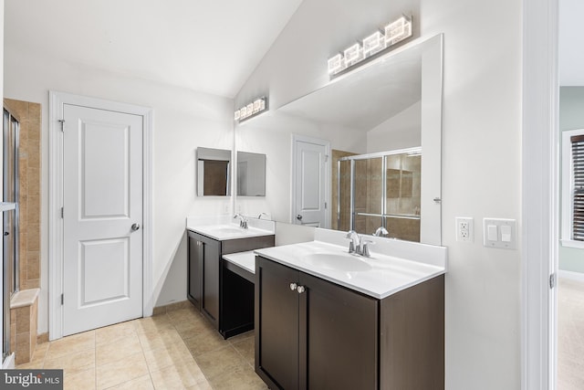 bathroom with vaulted ceiling, a stall shower, two vanities, and tile patterned flooring