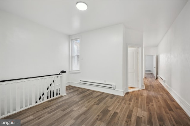 empty room with baseboards, wood finished floors, baseboard heating, and a baseboard heating unit